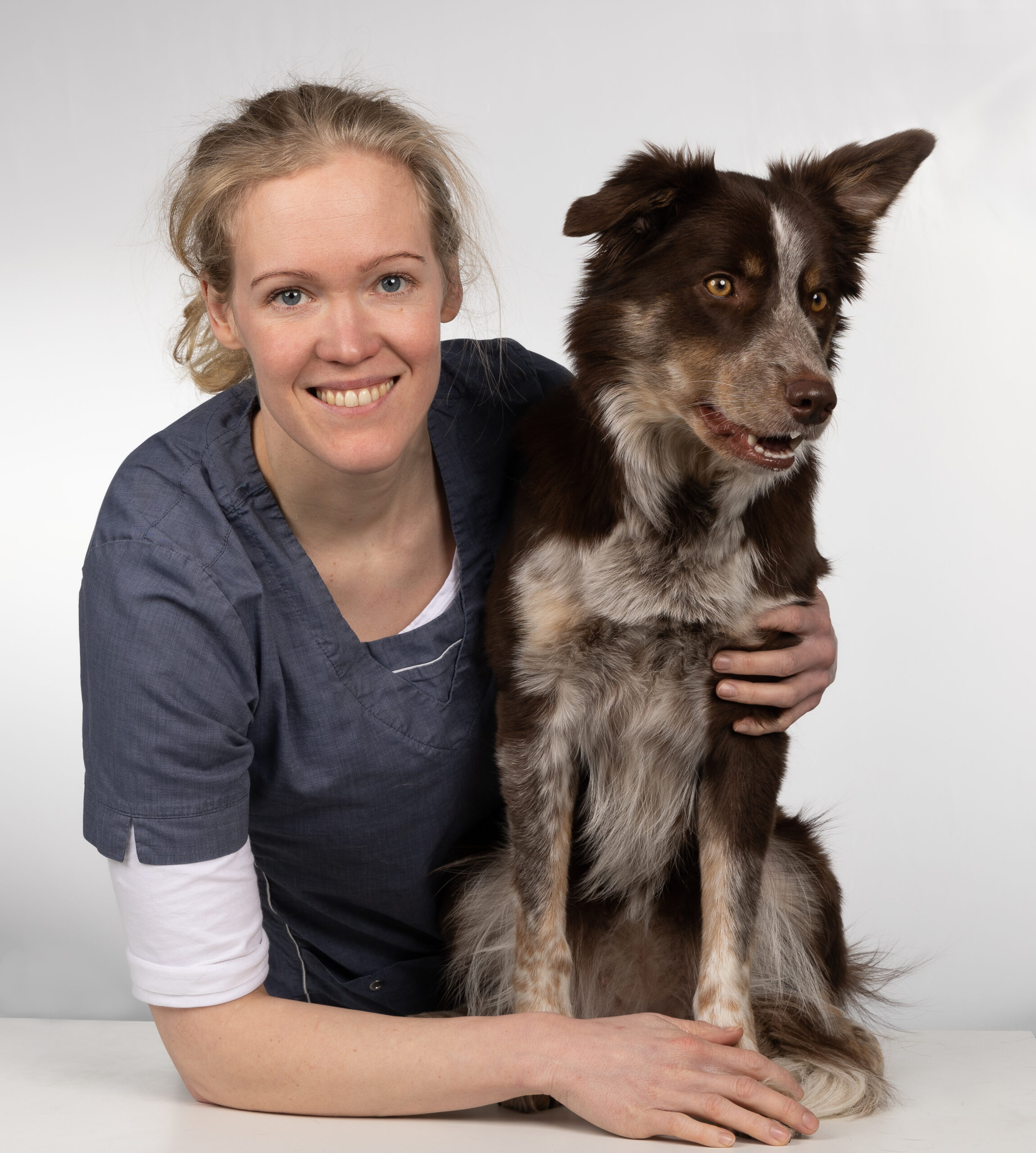 En veterinær som holder rundt en hund som sitter på et operasjonsbord.