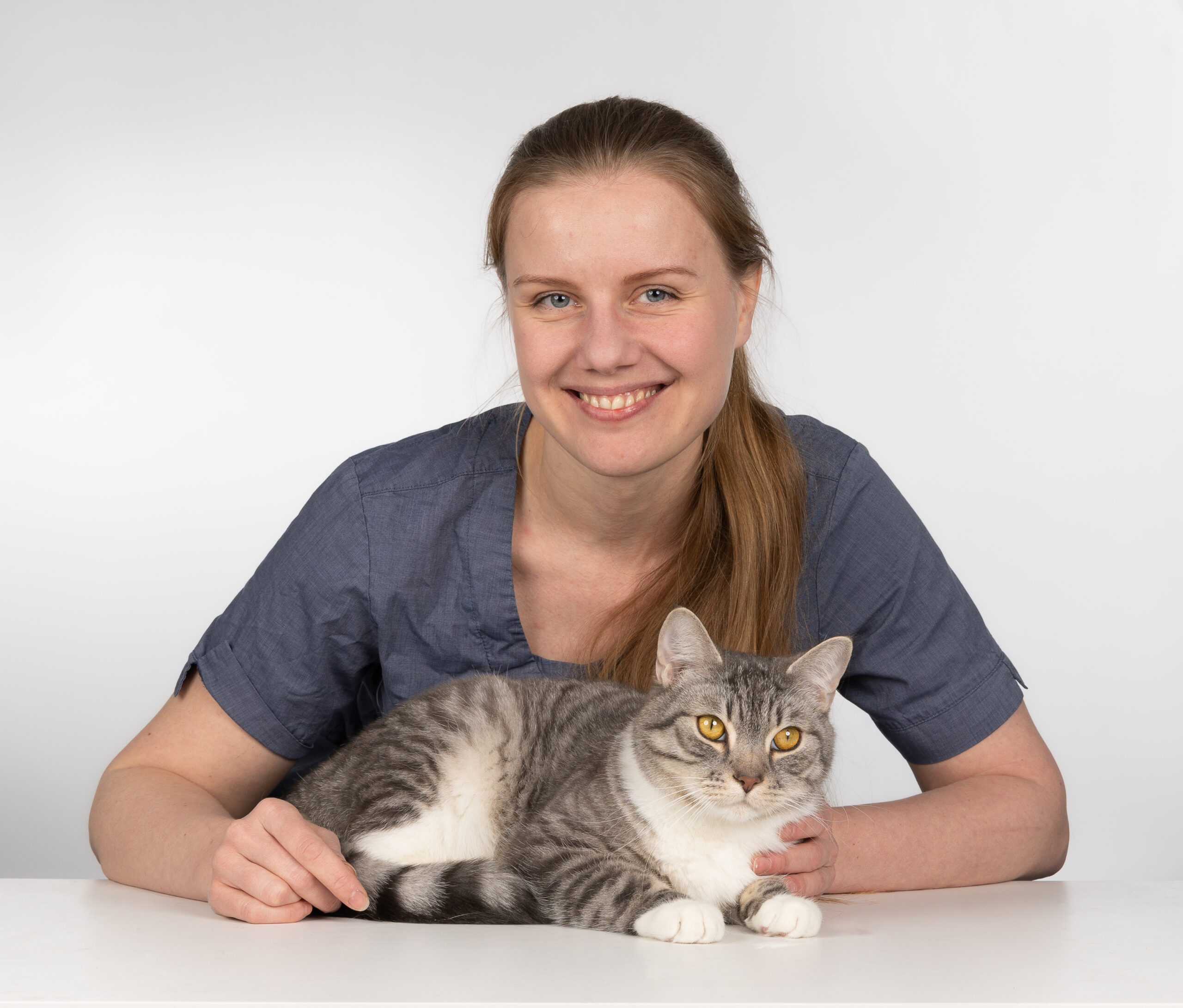 En veterinær som sitter og holder rundt en katt.